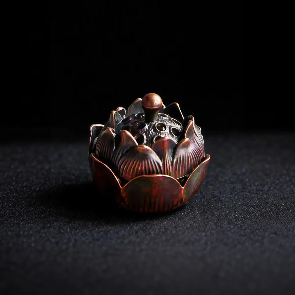 Decorative metal incense burner shaped like a lotus flower on a dark background