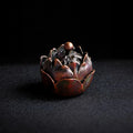 Decorative metal incense burner shaped like a lotus flower on a dark background