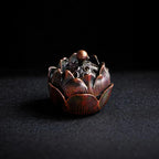 Decorative metal incense burner shaped like a lotus flower on a dark background