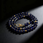 Navy blue beaded necklace with gold accents on a dark surface