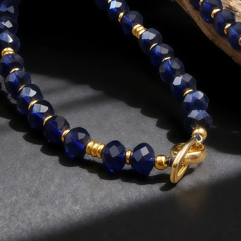 Beaded bracelet with blue beads and gold accents on a dark surface