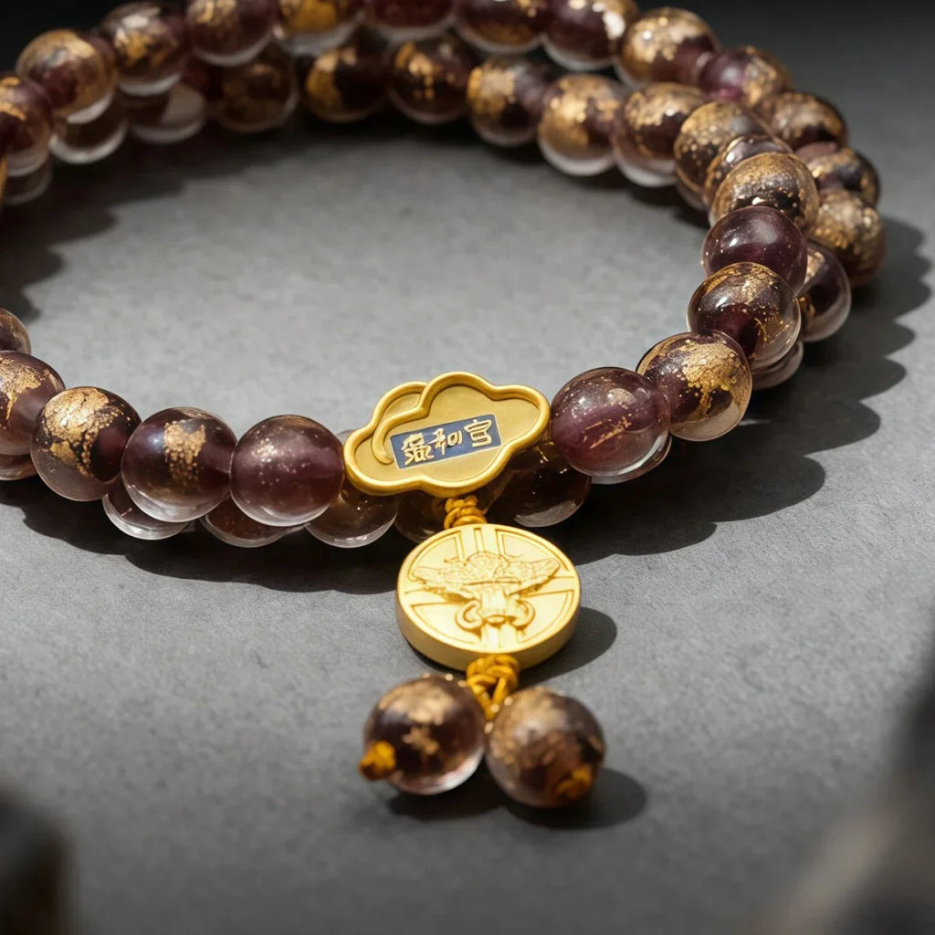 Liuli glass beaded bracelet with gold charms on a gray surface