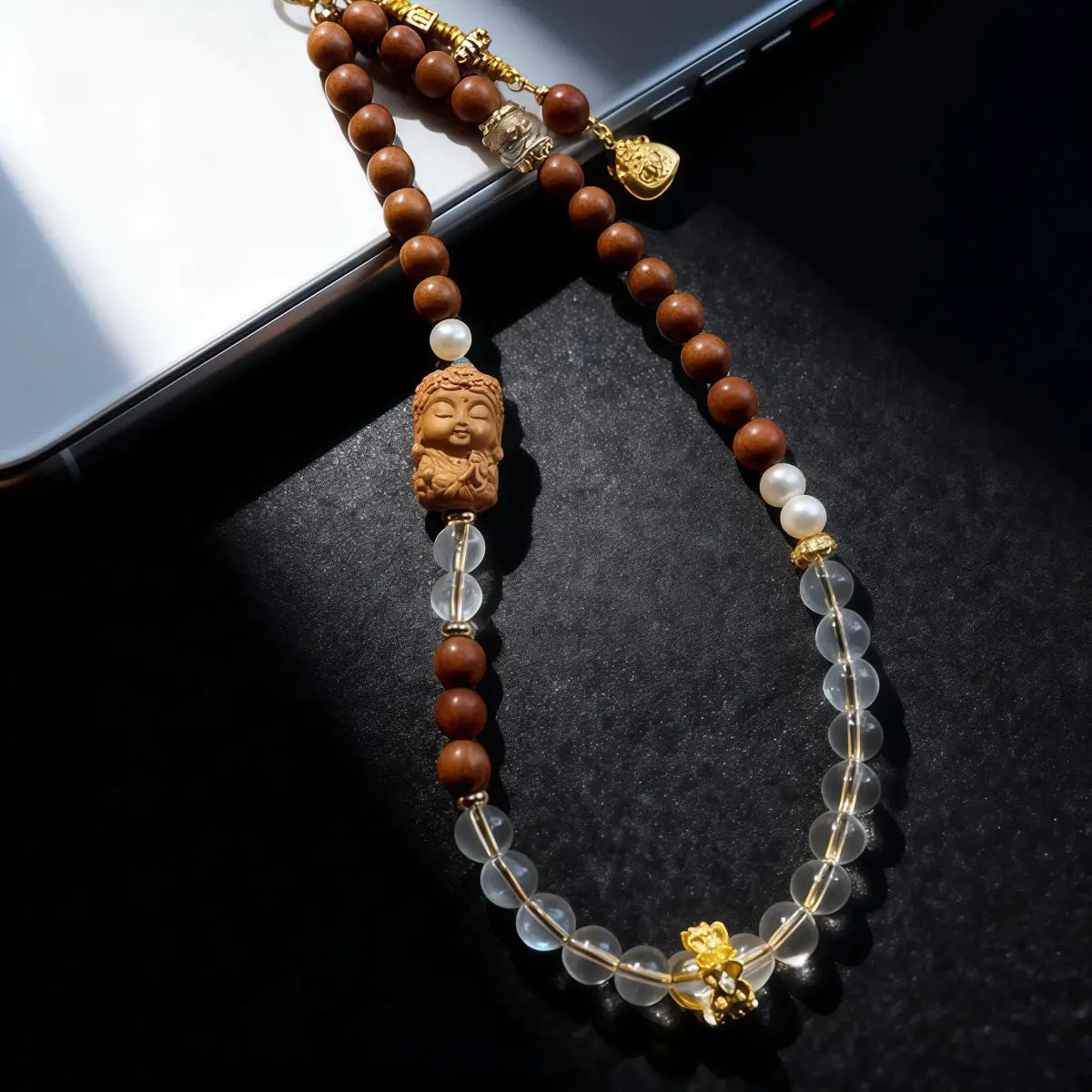 Beaded Phone Strap with wooden beads and a Buddha figure on a black surface