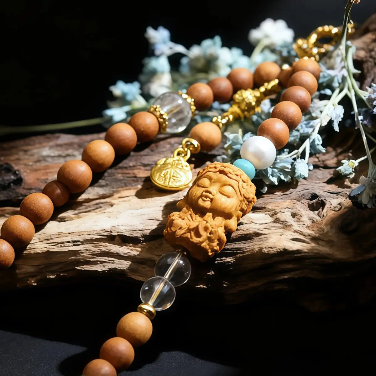 Sandalwood_Buddha_Charm_Phone_Strap with a Buddha pendant on a dark surface with flowers.