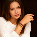 Woman wearing a incense beaded bracelet with a gold charm on a dark background