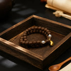 Tibetan incense beaded bracelet with a gold accent on a wooden tray
