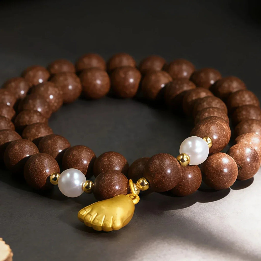 Brown incense beaded bracelet with a gold leaf charm on a dark background