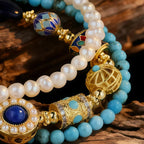 Close-up of a pearl and turquoise beaded bracelet with gold accents on a wooden surface.