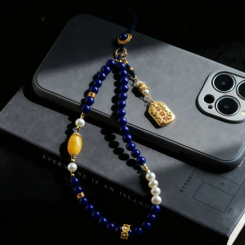 Decorative beaded phone charm on a smartphone with a dark background
