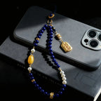 Decorative beaded phone charm on a smartphone with a dark background
