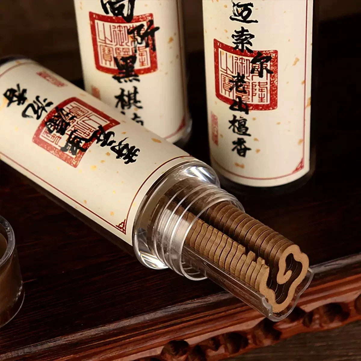 Traditional Chinese incense slice in a cylindrical holder with decorative scents labels on a wooden surface.
