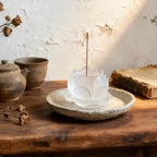 White liuli incense holder on a wooden surface with a teapot and books in the background.