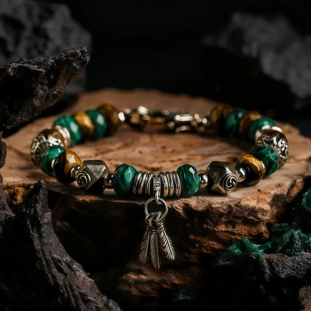 Tibetan Bracelet with green and gold beads and a feather charm on a wooden surface.