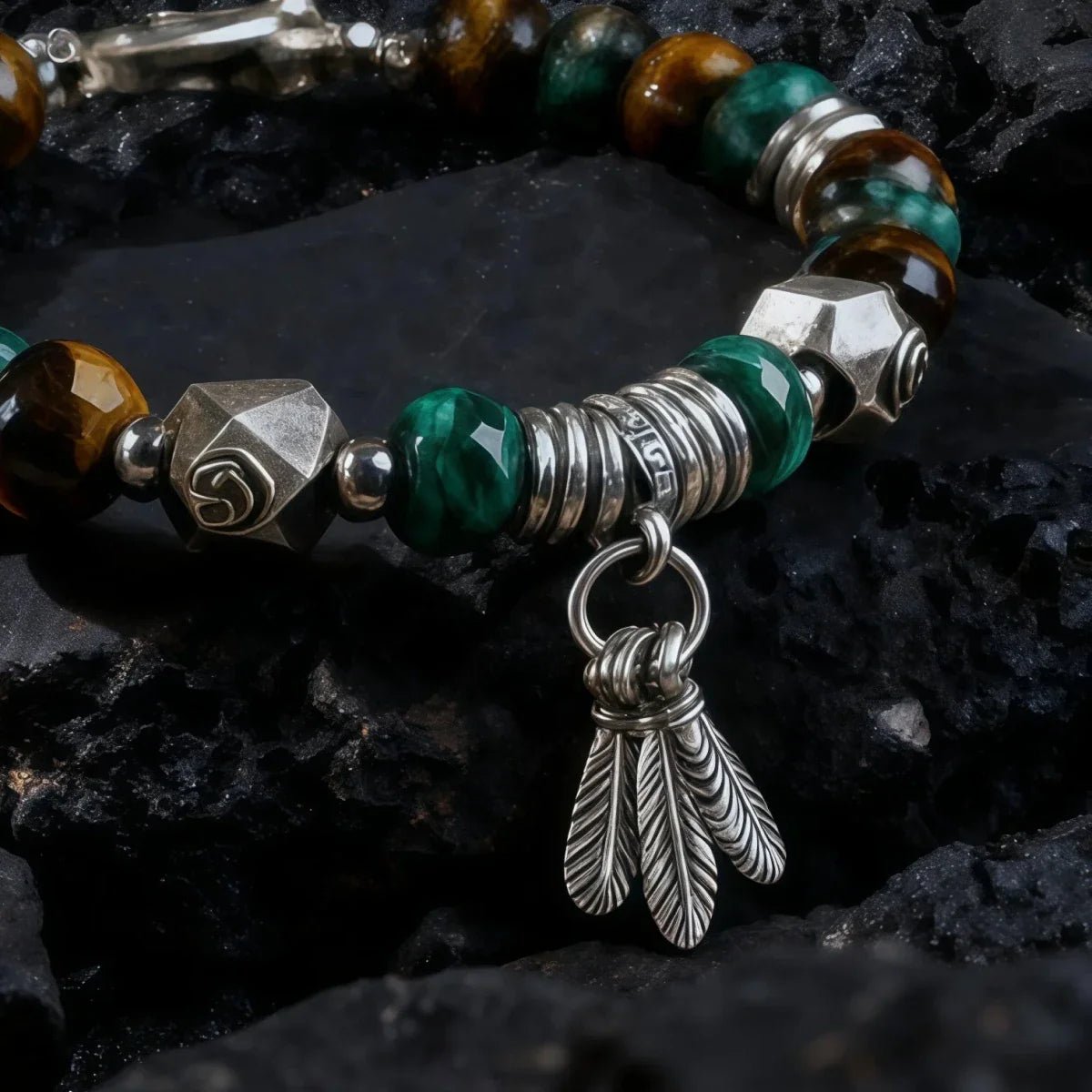Tibetan Bracelet with green beads, silver accents, and a feather charm on a dark stone background