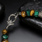 Tibetan Bracelet with green and brown beads and a silver star-shaped charm on a dark background