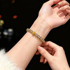 Close-up of a hand wearing a Gray Agate Fortune Bracelet with a dark background
