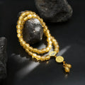 Gold liuli glass beaded bracelet with a tassel on dark volcanic rock