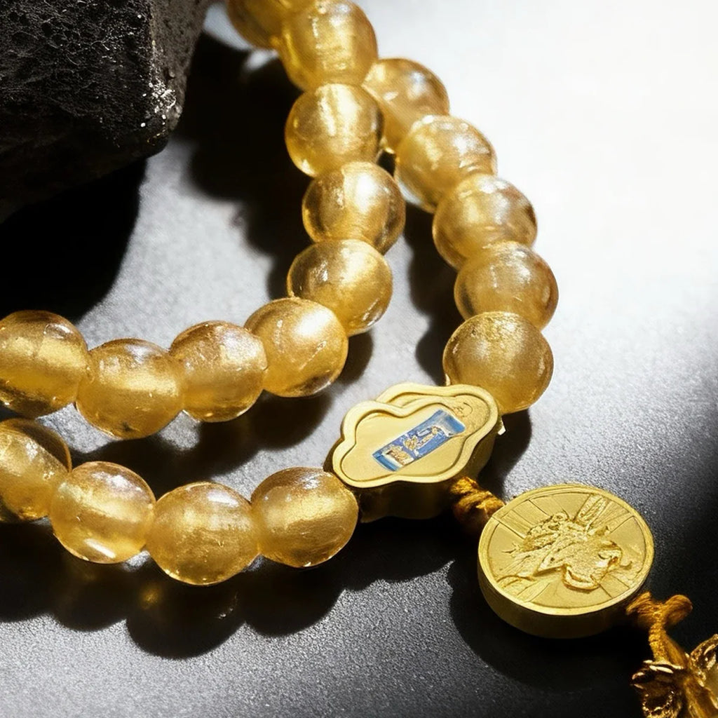 Gold liuli glass beaded bracelet with a decorative clasp on a reflective surface
