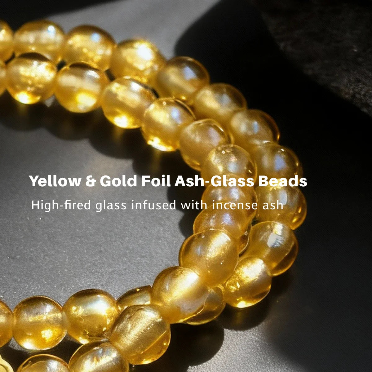 Yellow and gold foil ash glass beads on a dark surface