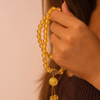 Hand holding a yellow liuli glass beaded bracelet against a neutral background
